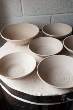 Seramik sanatçılarının ev yapımı çömlek atölyesinde fırının tepesinde çalışma sürüyor. Taş kaplar, çevrilmiş, kurutulmuş ve ateşe hazır..