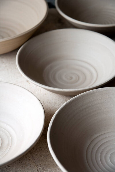 Work in progress standing on the top of the kiln in a ceramics artists home pottery studio. Stoneware bowls, turned, dried and ready to fire.