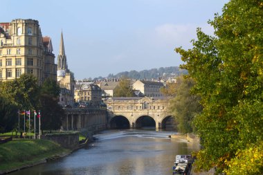 Bath, İngiltere - 10 Ekim 2010: İngiltere 'nin Somerset kentindeki Bath şehrinde Sonbahar güneşinde Avon Nehri' nin kıyılarını gezen ziyaretçiler. Bath, UNESCO 'nun dünya mirası sitesidir. Mimarisi ile ünlüdür.