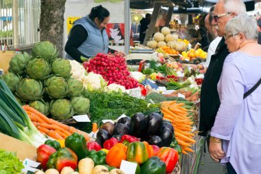 St-Cyprien, Dordogne, Fransa - 24 Eylül 2015: Müşteriler St-Cyprien, Dordogne, Fransa 'da pazar günü sergilenen renkli meyve ve sebzeleri inceliyorlar