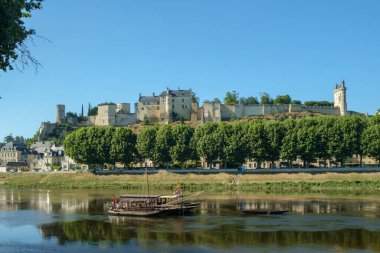 Chinon, Indre-et-Loire, Fransa - 26 Haziran 2018: Vienne Nehri 'nin yukarısındaki Chinon Şatosu turne teknelerinin güneşli bir yaz öğleden sonrasında Indre-et-Loire, Fransa' da demirlediği yer.