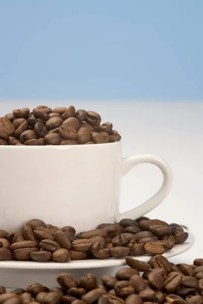 白杯中的咖啡豆和普通背景中的茶托 — 图库照片