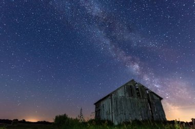 Gece gökyüzünde samanyolu terk edilmiş ahırın üstünde