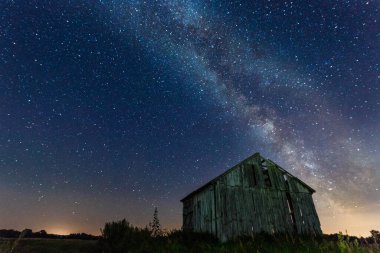 Gece gökyüzünde samanyolu terk edilmiş ahırın üstünde