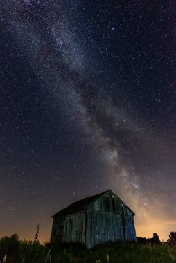 Gece gökyüzünde samanyolu terk edilmiş ahırın üstünde