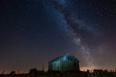 Gece gökyüzünde samanyolu terk edilmiş ahırın üstünde