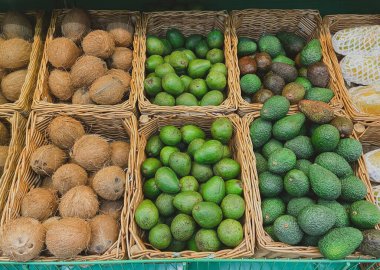 Meyve pazarı, sepetlerde taze sağlıklı meyvelerle çiftçi pazarı. Avokado ve hindistan cevizi tezgahta. Sağlıklı yaşam tarzı kavramı