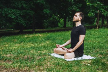 Genç bir adam yeşil bir tropikal bahçeyle çevrili yoga yaparken doğa, esneme, meditasyon ve sağlıkta dinleniyor. Muay Thai gibi çarpıcı teknikler, açık havada karate