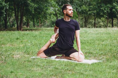 Genç bir adam yeşil bir tropikal bahçeyle çevrili yoga yaparken doğa, esneme, meditasyon ve sağlıkta dinleniyor. Muay Thai gibi çarpıcı teknikler, açık havada karate