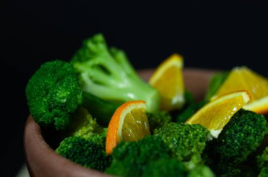 Yeşil brokoli sebzeli ahşap tabak, fasulye ve güzel siyah ve sarı bir arka plan..