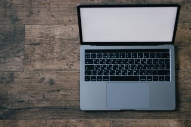 Ahşap arkaplan görünümlü dizüstü bilgisayar, beyaz ekran ve metin için boşluk. Modern dizüstü