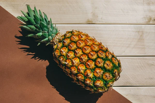 Sarı-beyaz arka planda olgun sulu tropikal ananas. Mesaj için yer var. Tahta bir masada ananas.