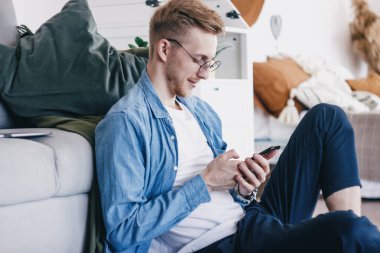 Evde elinde cep telefonu olan genç bir adam. Evdeki telefonu kullanan genç bir adamın yakın çekimi. Bir adam arkadaşlarıyla cep telefonuyla iletişim kurar. Evden çalışan genç iş adamları.