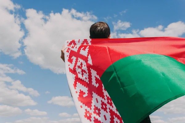 Протести в Мінську. Молодий чоловік тримає білоруський прапор проти блакитного неба. Вільна країна, вільна Білорусь — стокове фото