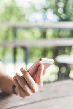 Kadın el Cafe yeşil doğa bokeh arka plan ile akıllı telefon kullanarak. Teknoloji ve iş kavramının alanı kopyalayın. Sığ derinlik-in tarla. Vintage sesi filtre renk stili.