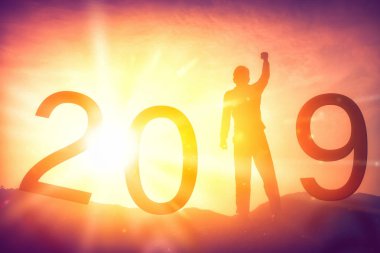 Happy new year ve tatil kavramı. Adam el üstünde tepe-in dağ ve numarası 2019 günbatımı gökyüzü ve bulut arka plan ile yükselterek. Vintage sesi filtre efekti renk stili.