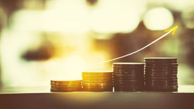 Para Finans ve iş kavramı. Tablo satırında bozuk para yığını ile pozlama eğilim grafiği yukarı çift ve renkli bokeh güneş ışık arka plan bulanıklık. Vintage sesi filtre efekti renk stili.