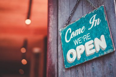 Kafenin önündeki tahta kapıya asılı açık tabela. İş hizmeti ve yemek konsepti. Klasik ton filtre efekti renk biçimi.