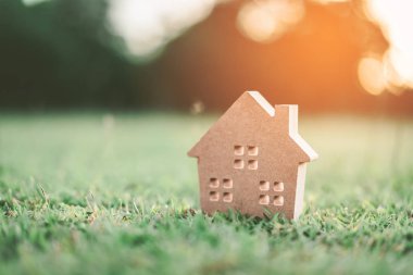 Ev ve yaşam kavramının alanı kopyalayın. Küçük model ev güneş ışığı arka plan ile yeşil çimenlerin üzerinde. Vintage sesi filtre efekti renk stili.