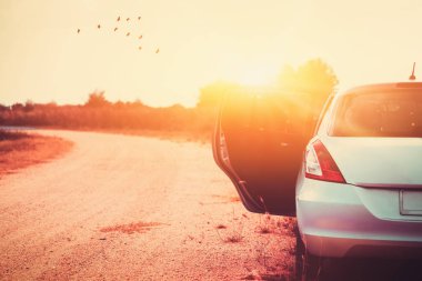 Köy yolunda ve günbatımı gökyüzü arka plan üzerinde uçan kuşlar, beraber seyahat araba. Yaz tatili ve özgürlük kavramı macera seyahat. Vintage sesi filtre efekti renk stili.