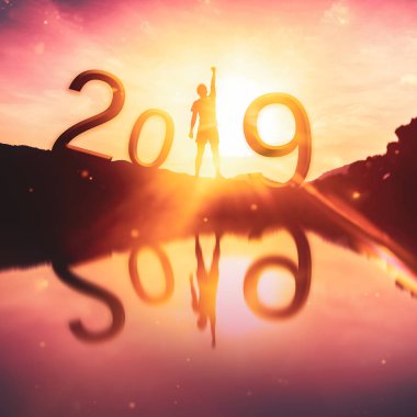 Happy new year ve tatil kavramı. Adam el üstünde tepe-in dağ ve günbatımı gökyüzü ve bulut arka plan nehir su yansıması olan sayı 2019 yükselterek. Vintage sesi filtre efekti renk stili.