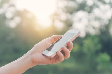 Açık doğa parkında akıllı telefon kullanan bir kadın. Gökyüzü soyut arkaplanı var. Uzay teknolojisi ve seyahat doğası tatil konseptini kopyalayın. Klasik ton filtre efekti renk biçimi.