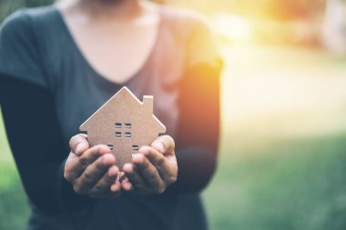 Kadın el küçük ev modeli. Aile hayatı ve iş gayrimenkul konsept. Vintage sesi filtre efekti renk stili.