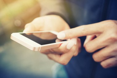 Adam el yakından tutun park açık sokak arka plan üzerinde akıllı telefon kullanarak. Teknoloji iş alanı kopyalayın ve tatil kavramı seyahat. Vintage sesi filtre efekti renk stili.
