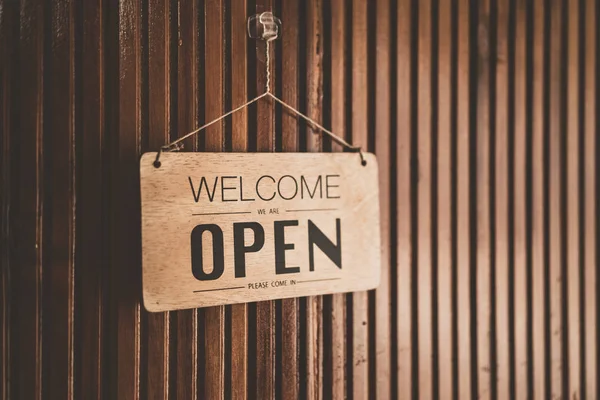 Open sign broad hanging on wood door front of cafe. Business service and food concept. Vintage tone filter effect color style.