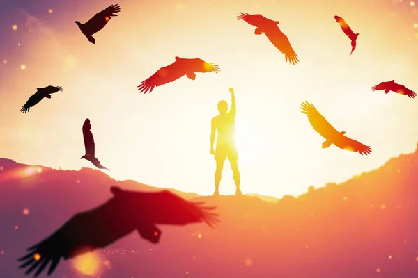 Man raise hand up on top of mountain and sunset sky with eagle birds fly abstract background. Copy space freedom travel adventure and business victory concept. Vintage tone filter effect color style.