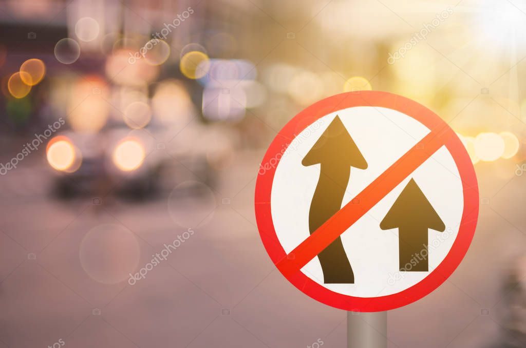 No Overtaking sign on blur traffic road with colorful bokeh light abstract background. Copy space of transportation and travel concept. Retro tone filter color style.