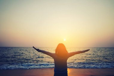 Sahilde ve adada, günbatımında gökyüzünde yükselen kadın mekânını kopyalayın. Özgürlük ve seyahat macera konsepti. Klasik ton filtre efekti renk biçimi.