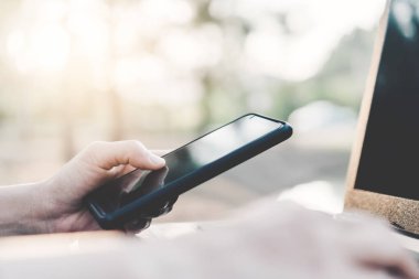 Kadın eli açık doğa parkı ve günbatımı gökyüzü bokeh ışık arka plan ile akıllı telefon ve dizüstü bilgisayar kullanarak.