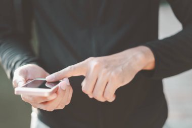 Adam el yakından tutun park açık sokak arka plan üzerinde akıllı telefon kullanma.