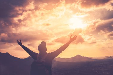 Backpacker adam altında el kadar günbatımı gökyüzü ile dağın zirvesinde yükseltmek ve arka plan bulutlar soyut.