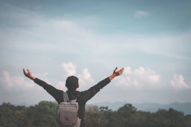 Backpacker adam altında el kadar mavi gökyüzü ve bulutlar beyaz arka plan ile dağın zirvesinde yükseltmek.