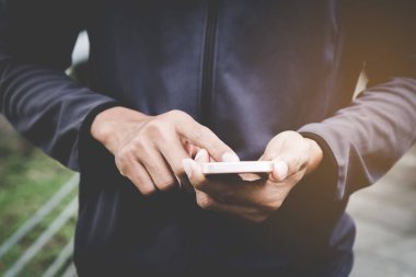 Adam el yakından tutun park açık sokak arka plan üzerinde akıllı telefon kullanma.