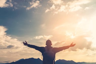 Backpacker adam altında el kadar günbatımı gökyüzü ile dağın zirvesinde yükseltmek ve arka plan bulutlar soyut.