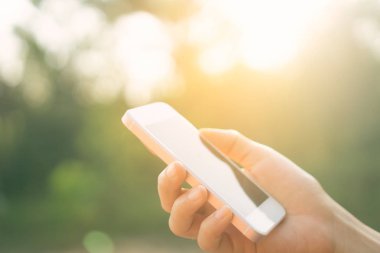 Kadın eli açık doğa Park günbatımı gökyüzü arka plan ile akıllı telefon kullanma.