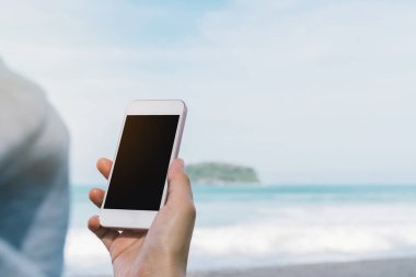 Akıllı telefon plaj arka plan kullanarak kadın el kopya alanı.