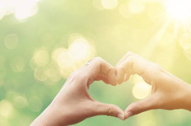 Eller şekil doğa yeşil bokeh güneş ışık parlama üzerinde kalp ve yaprak arka plan bulanıklık.