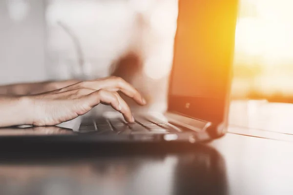 Woman hand using keyboard laptop on wood table in coffee shop.