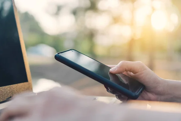 Жінка рука використовує смартфон і ноутбук у відкритому природному парку і небо заходу сонця з боке легким абстрактним фоном . — стокове фото