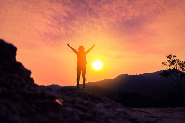 Copy space of woman rise hand up on top of mountain and sunset sky abstract background.