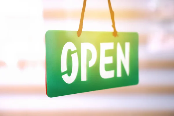 Open sign hanging on mirror door front of office room with sun light through window. — Stock Photo, Image