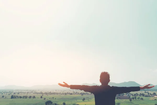 Mochilero hombre levantar la mano en la cima de la montaña con el cielo puesta del sol y las nubes fondo abstracto . — Foto de Stock