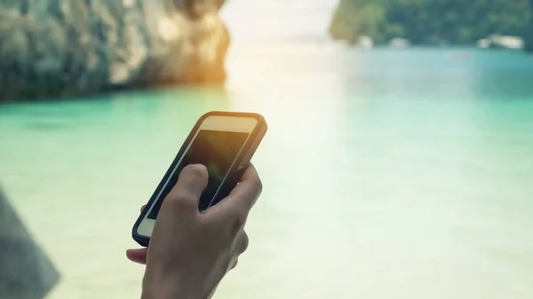 Miejsce kobiety ręki za pomocą inteligentnego telefonu w tle plaży. — Zdjęcie stockowe