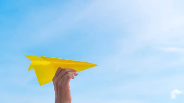Woman hand holding paper airplane on blue sky and white clouds abstract background. — Stock Photo, Image