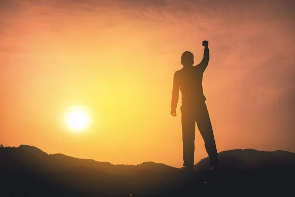 Copy space of man rise hand up on top of mountain and sunset sky abstract background.