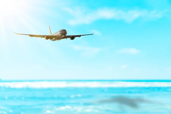 Travel vacation and transport concept. Copy space of airplane flying on blur tropical beach with bokeh sun light wave abstract background. — Stock Photo, Image